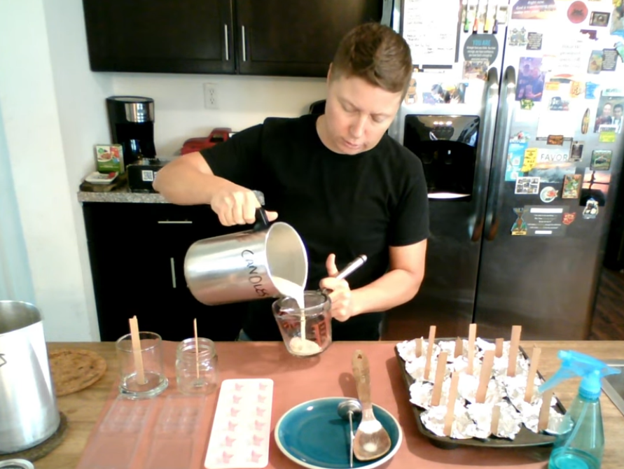Candle maker pouring wax into jars